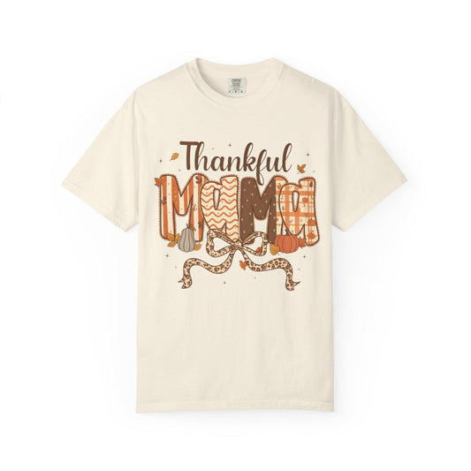 Beige t-shirt with 'Thankful Mom' text and autumn-themed graphics on a white background