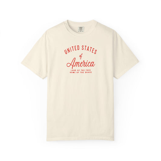 Ivory patriotic USA t-shirt featuring “United States of America” red graphic text with Land of the Free Home of the Brave design for 4th of July and Independence Day wear
