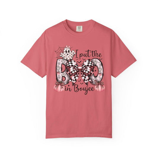 Peony short-sleeve t-shirt with a playful Halloween-themed design that reads “I put the BOO in Boujee.” The word “BOO” is decorated with black and pink patterns, including leopard print and buffalo plaid, accented by a large checkered bow. Surrounding the text are cute seasonal details such as pink pumpkins, a ghost, bats, and a spider web, giving the shirt a stylish and boujee spooky vibe.