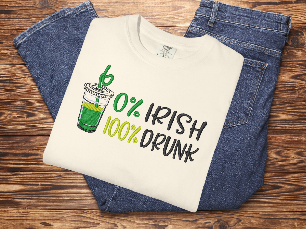 Ivory t-shirt with '10% Irish 100% Drunk' design on a wooden surface with jeans.