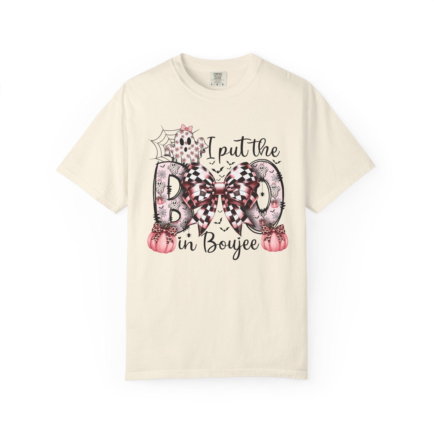 Ivory short-sleeve t-shirt with a playful Halloween-themed design that reads “I put the BOO in Boujee.” The word “BOO” is decorated with black and pink patterns, including leopard print and buffalo plaid, accented by a large checkered bow. Surrounding the text are cute seasonal details such as pink pumpkins, a ghost, bats, and a spider web, giving the shirt a stylish and boujee spooky vibe.