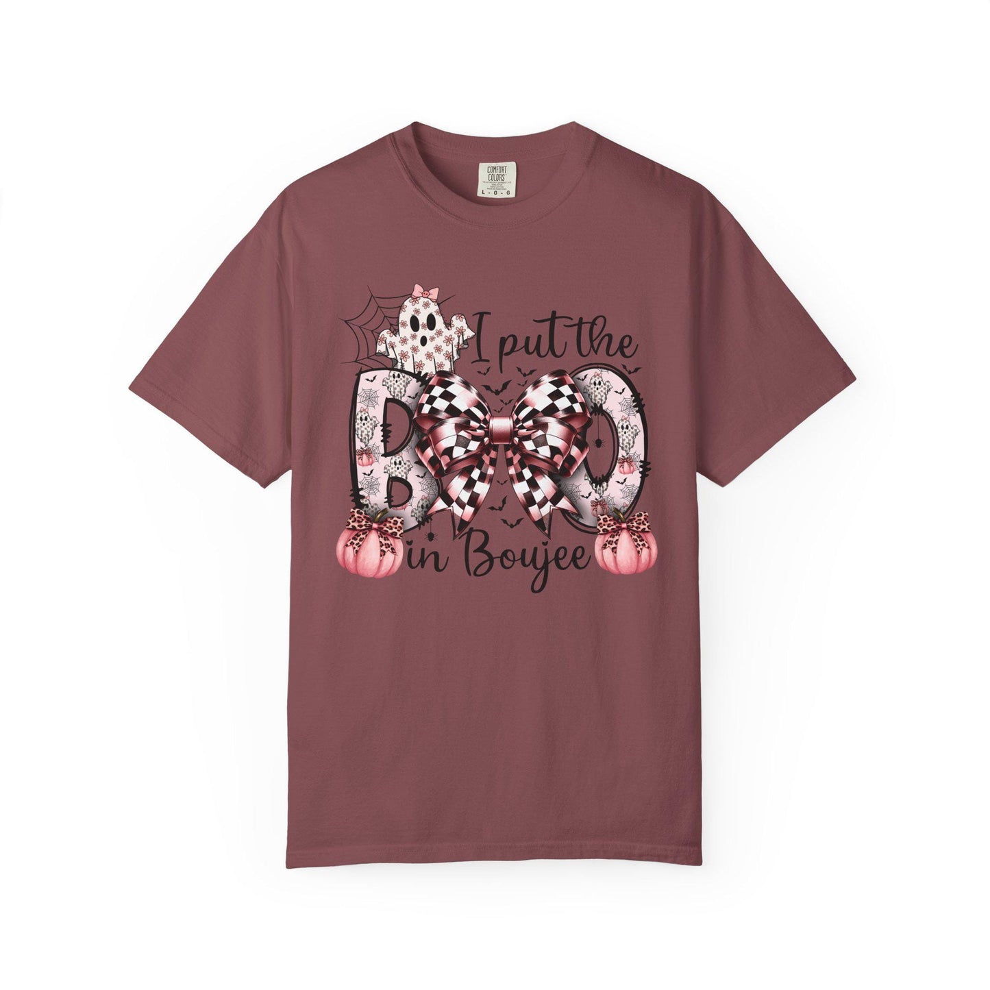 Brick short-sleeve t-shirt with a playful Halloween-themed design that reads “I put the BOO in Boujee.” The word “BOO” is decorated with black and pink patterns, including leopard print and buffalo plaid, accented by a large checkered bow. Surrounding the text are cute seasonal details such as pink pumpkins, a ghost, bats, and a spider web, giving the shirt a stylish and boujee spooky vibe.